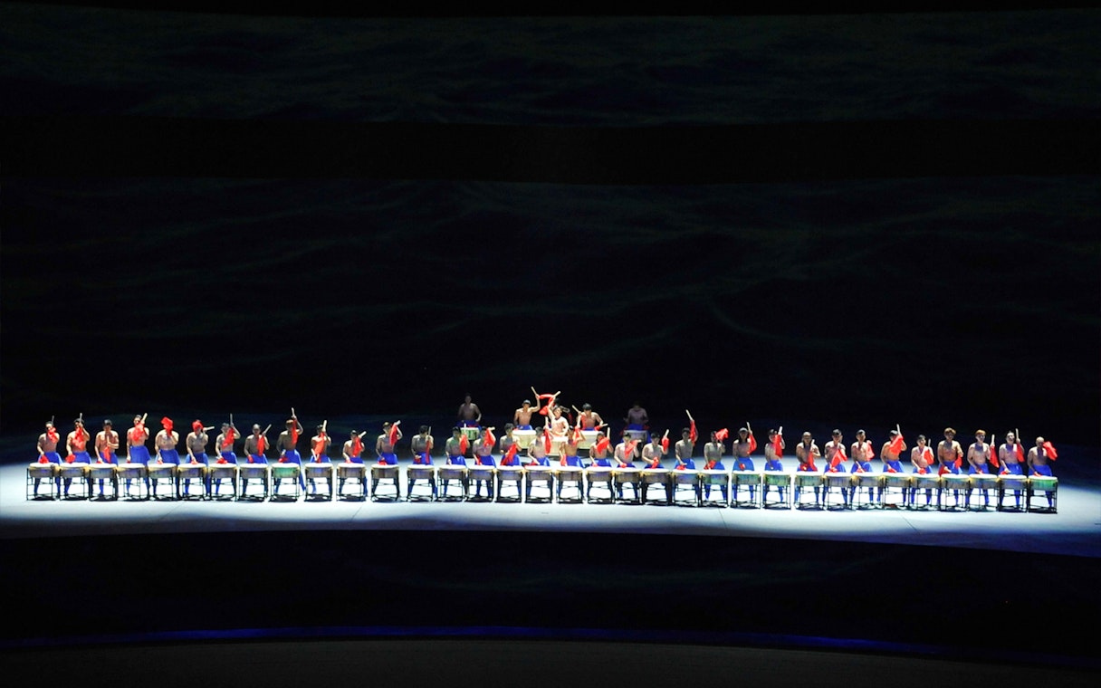 Performers on a multi-lifting platform in a synchronized drumming show.