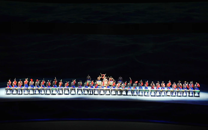 Performers on a multi-lifting platform in a synchronized drumming show.