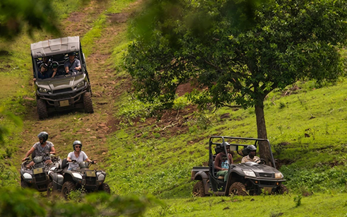 People driving buggies and ATVs on a grassy trail during a Bel Ombre buggy tour.
