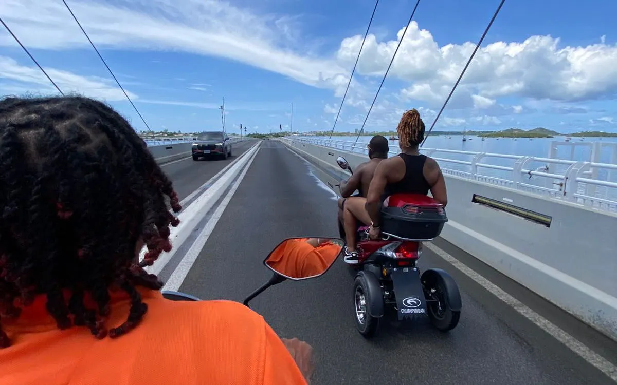 Scooter tour crossing a bridge in Sint Maarten with scenic ocean views.