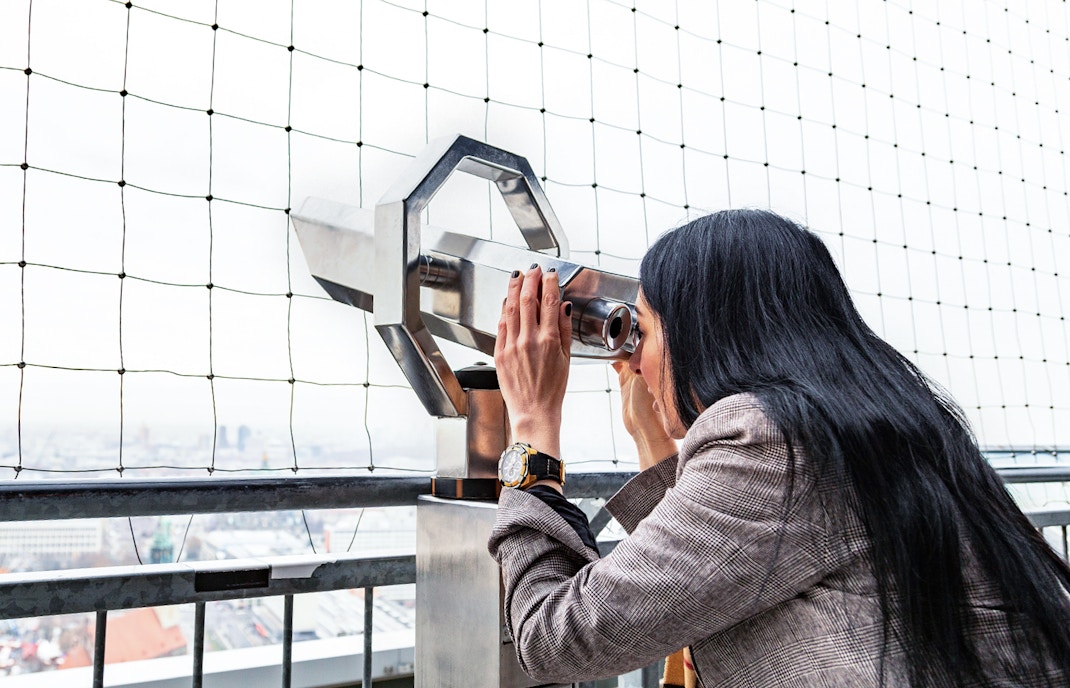 Eine Frau schaut auf dem Berliner Fernsehturm durch ein Fernglas