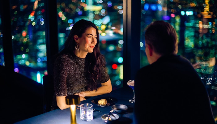 Couple dining at Melbourne Skydeck with city lights view.