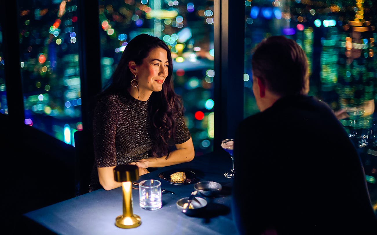 Couple dining at Melbourne Skydeck with city skyline view.