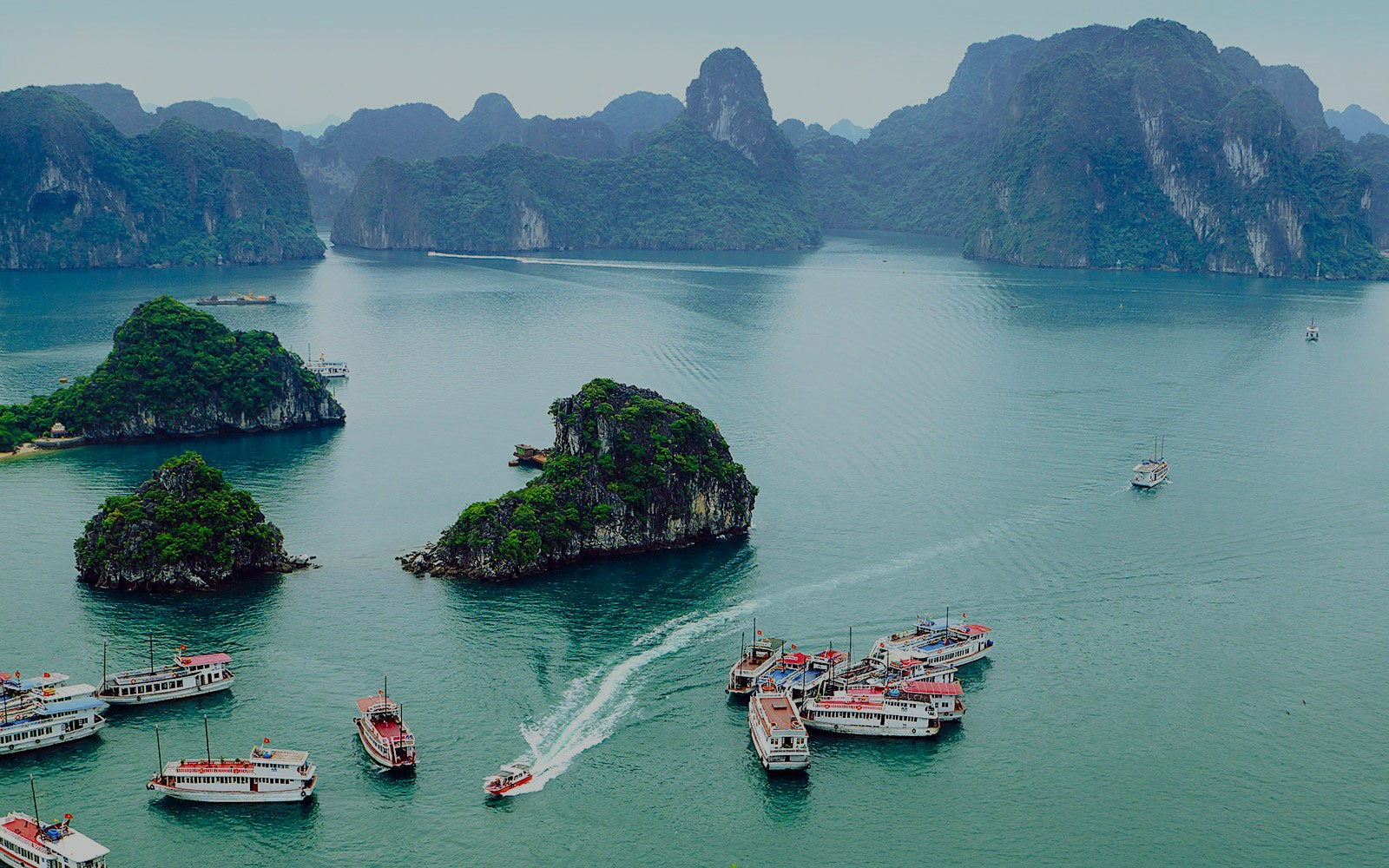 Boats navigating around limestone islands near Titop Island, Vietnam.