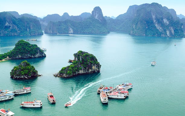 Boats navigating around limestone islands near Titop Island, Vietnam.