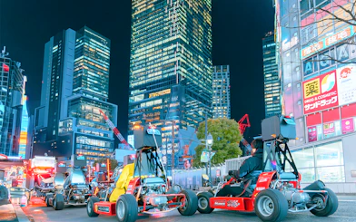 Go-karts driving through illuminated city streets at night.