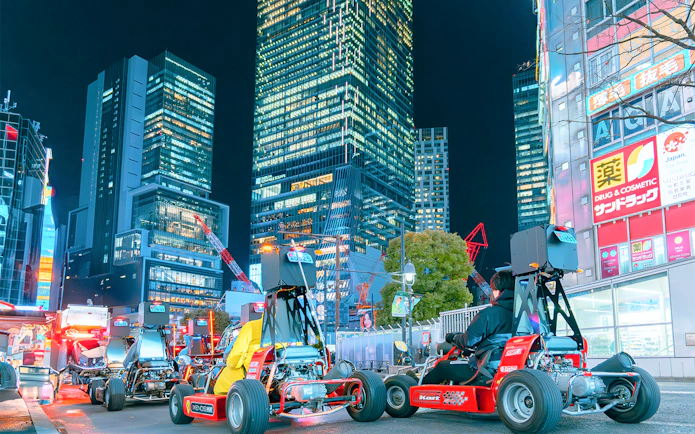 Go-karts driving through illuminated city streets at night.