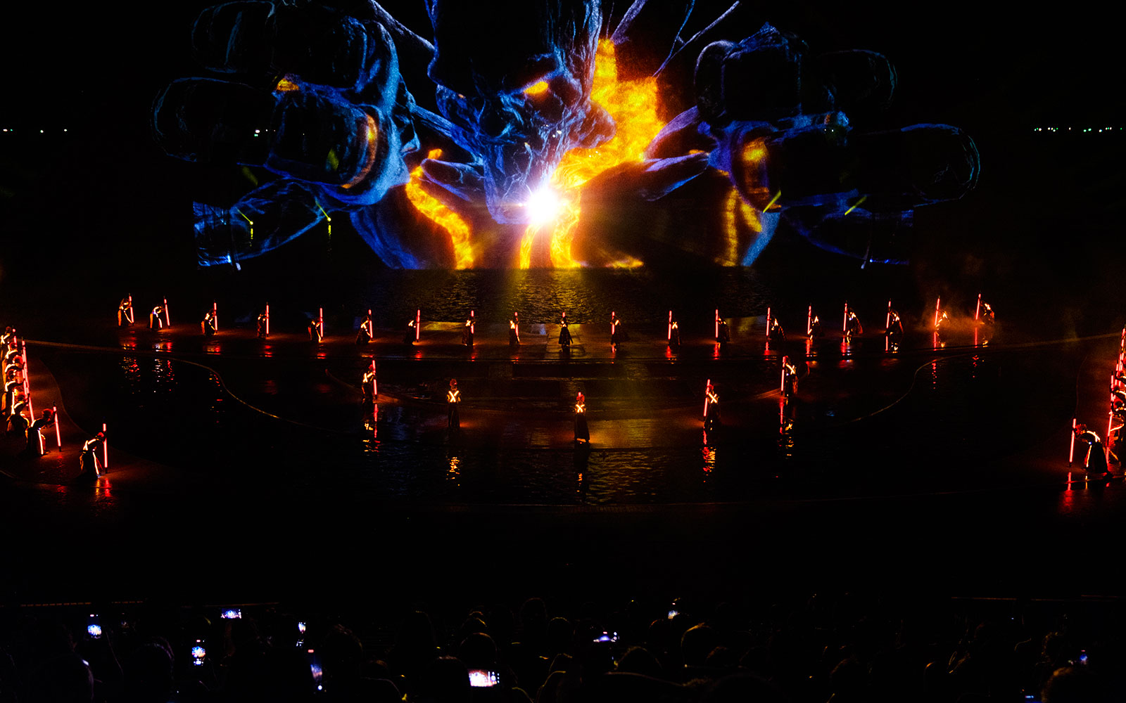 Performers with illuminated props at Kiss of the Sea Show, vibrant light display in background.