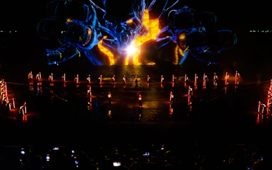 Performers with illuminated props at Kiss of the Sea Show, vibrant light display in background.
