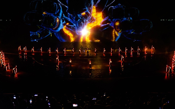 Performers with illuminated props at Kiss of the Sea Show, vibrant light display in background.