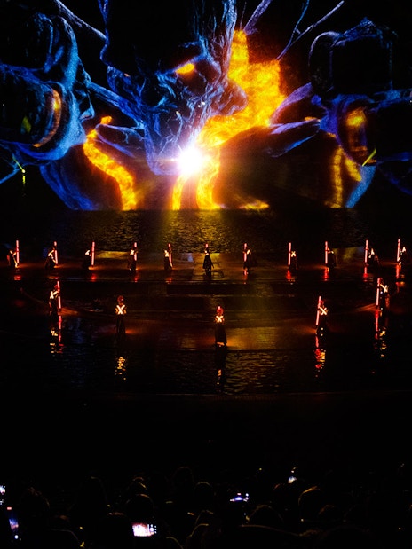 Performers with illuminated props at Kiss of the Sea Show, vibrant light display in background.