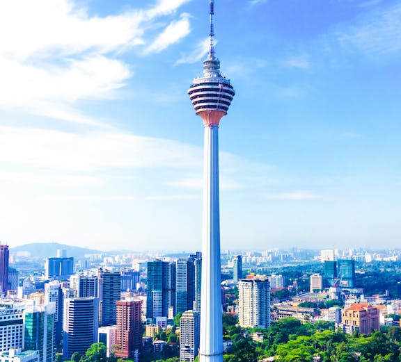 KL Tower rising above Kuala Lumpur skyline with surrounding cityscape.