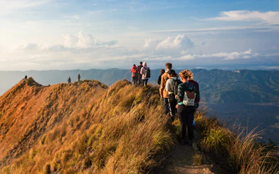 Group trekking along Mount Batur ridge at sunrise, Bali.