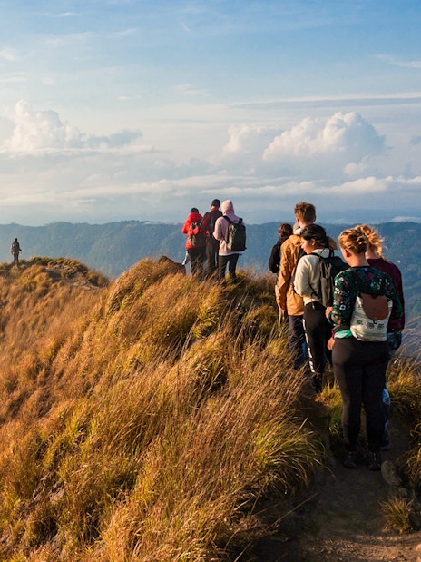 Group trekking along Mount Batur ridge at sunrise, Bali.