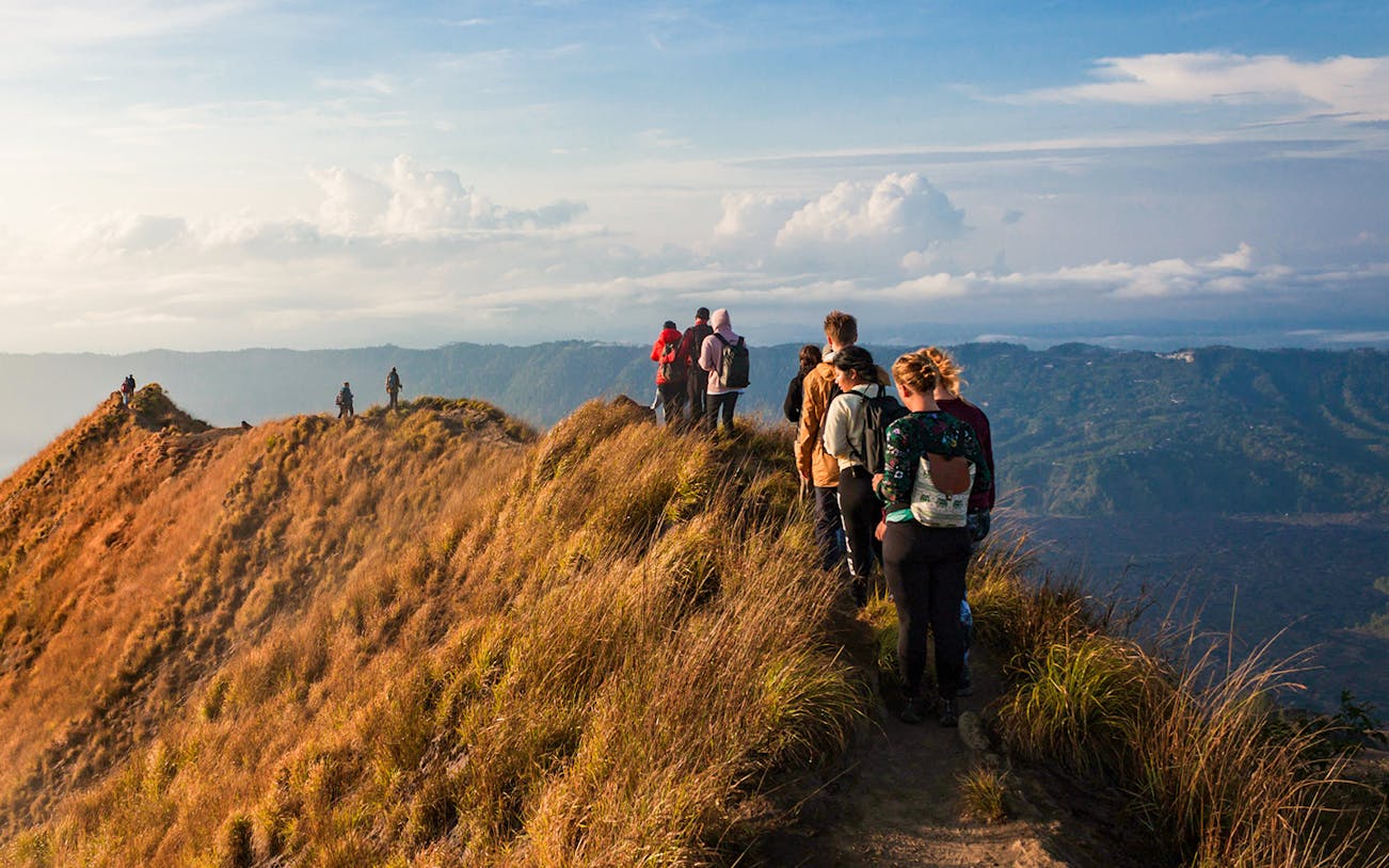 Group trekking along Mount Batur ridge at sunrise, Bali.