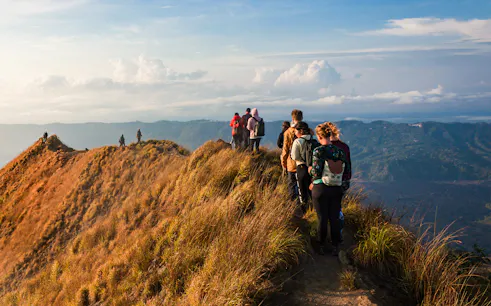 Group trekking along Mount Batur ridge at sunrise, Bali.