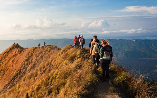 Group trekking along Mount Batur ridge at sunrise, Bali.