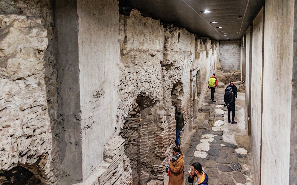 Visitors exploring ancient underground ruins at Neapolis Sotterrata in Naples, Italy.