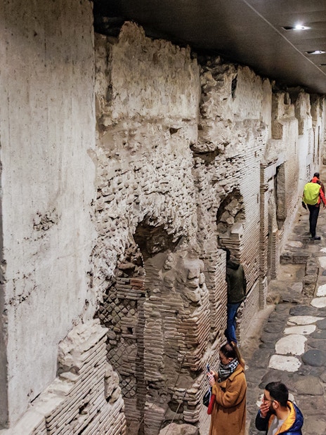 Visitors exploring ancient underground ruins at Neapolis Sotterrata in Naples, Italy.