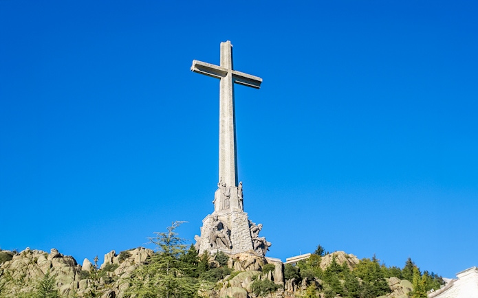 Cross on mountain at Valley of the Fallen, Spain, under clear blue sky.