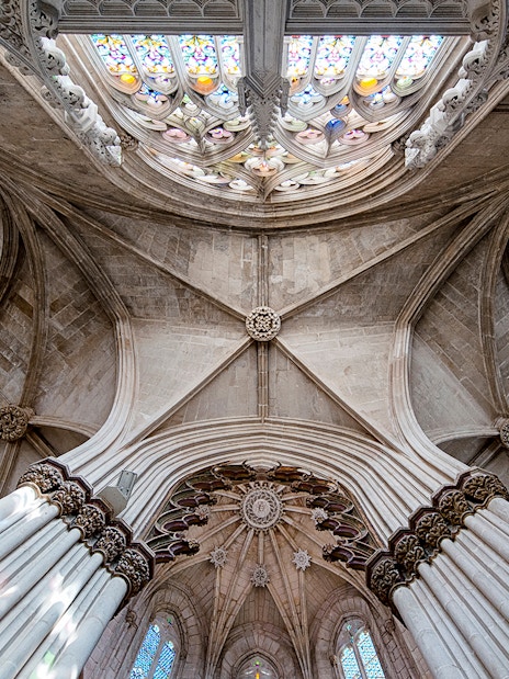 Batalha Monastery ceiling with intricate stone arches and stained glass windows.