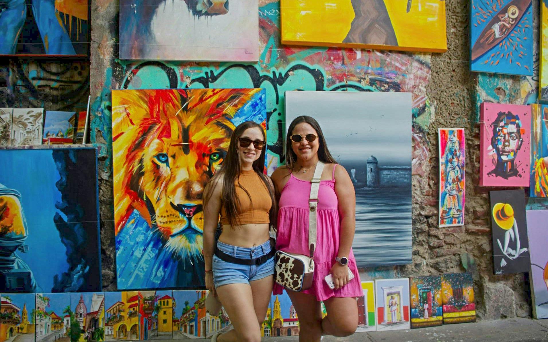 Travelers in front of vibrant street art in Getsemaní, Cartagena.