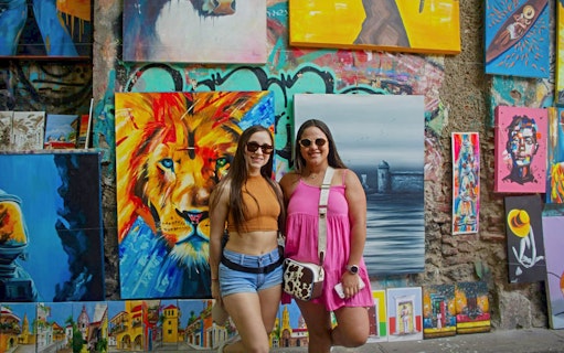 Travelers in front of vibrant street art in Getsemaní, Cartagena.