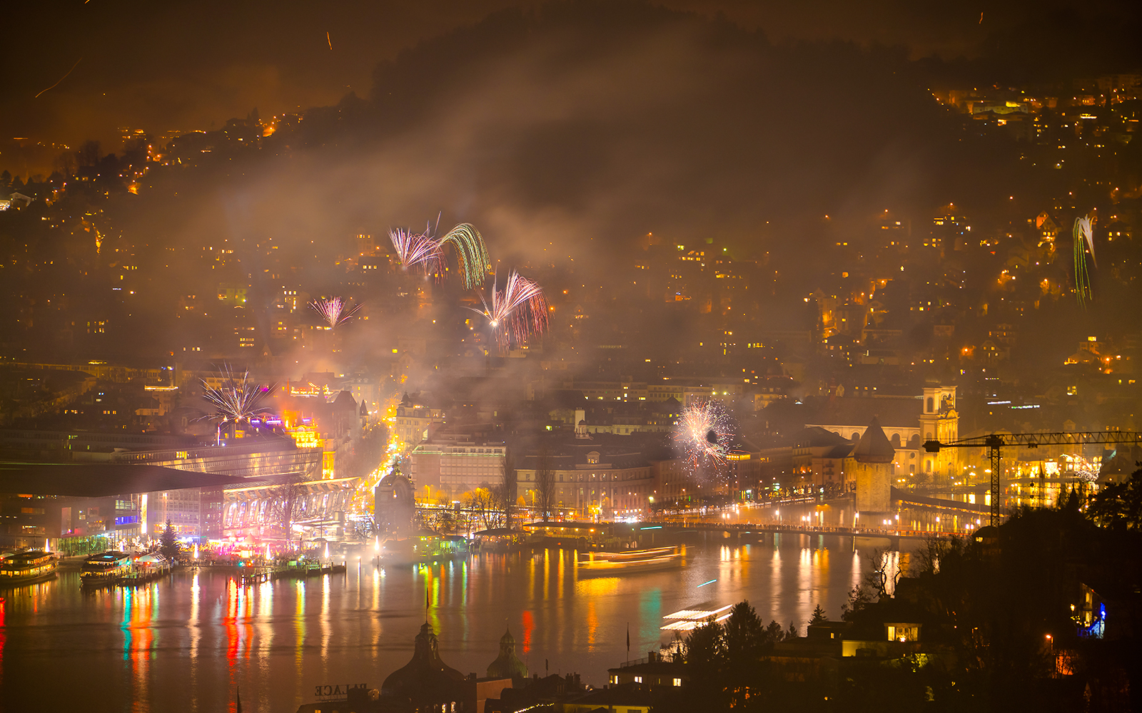 Fireworks over Lucerne's central area during New Year celebration, reflecting on the lake.