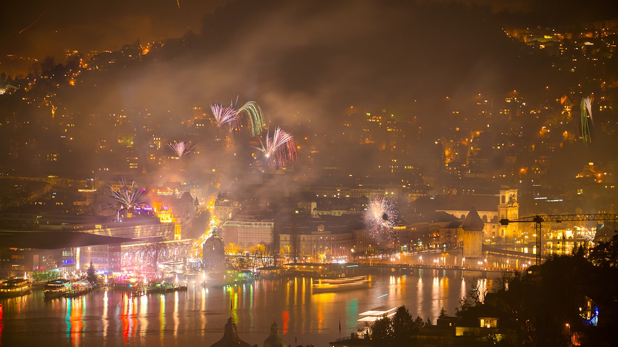 Fireworks over Lucerne's central area during New Year celebration, reflecting on the lake.