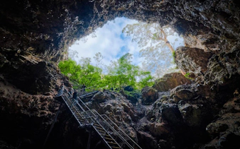Visitors exploring Margaret River Cave via metal staircase, surrounded by rock formations and greenery.
