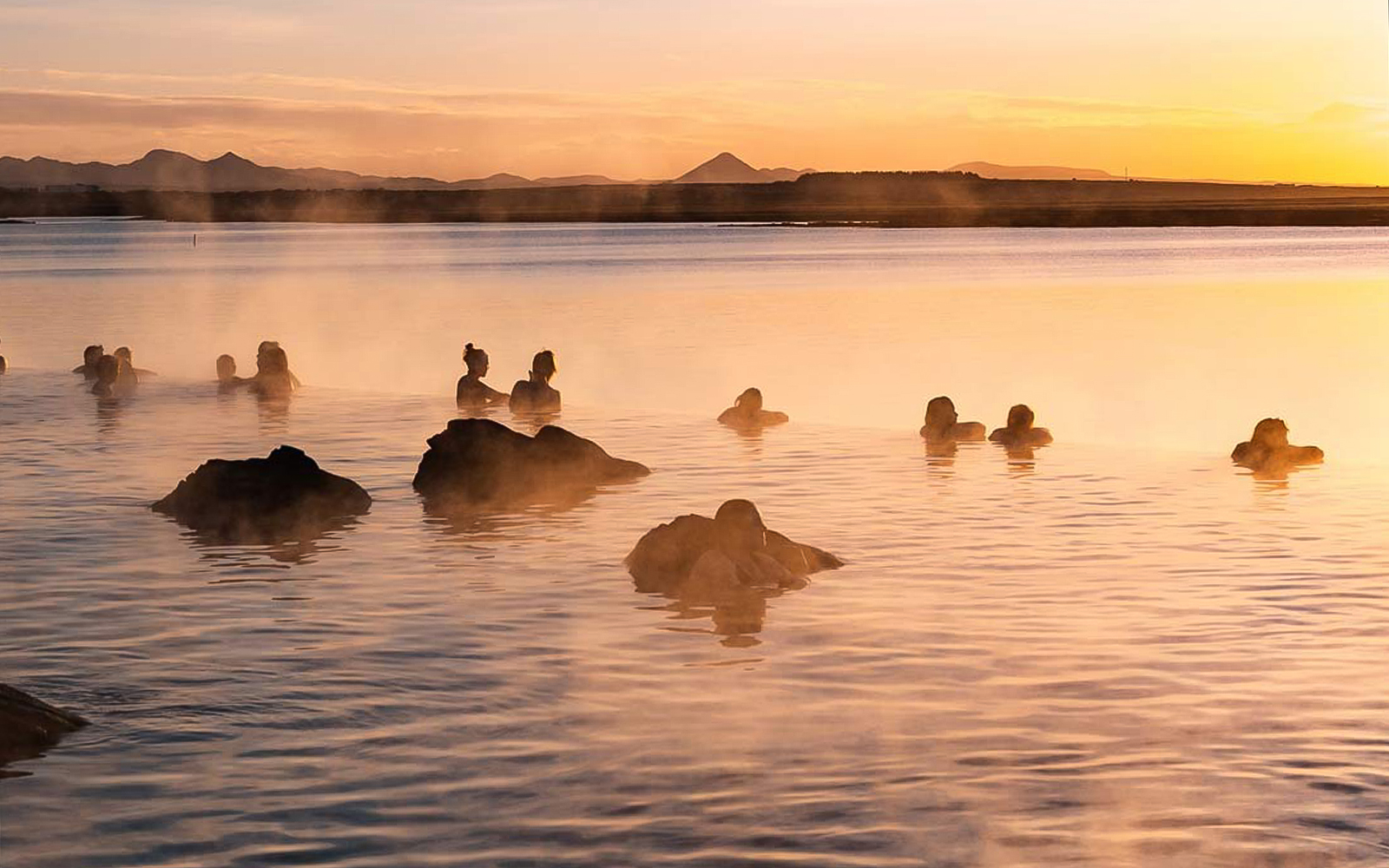 Guests relaxing in the warm waters of Sky Lagoon at sunset.