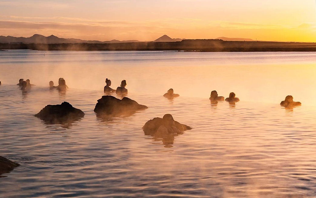 Guests relaxing in the warm waters of Sky Lagoon at sunset.