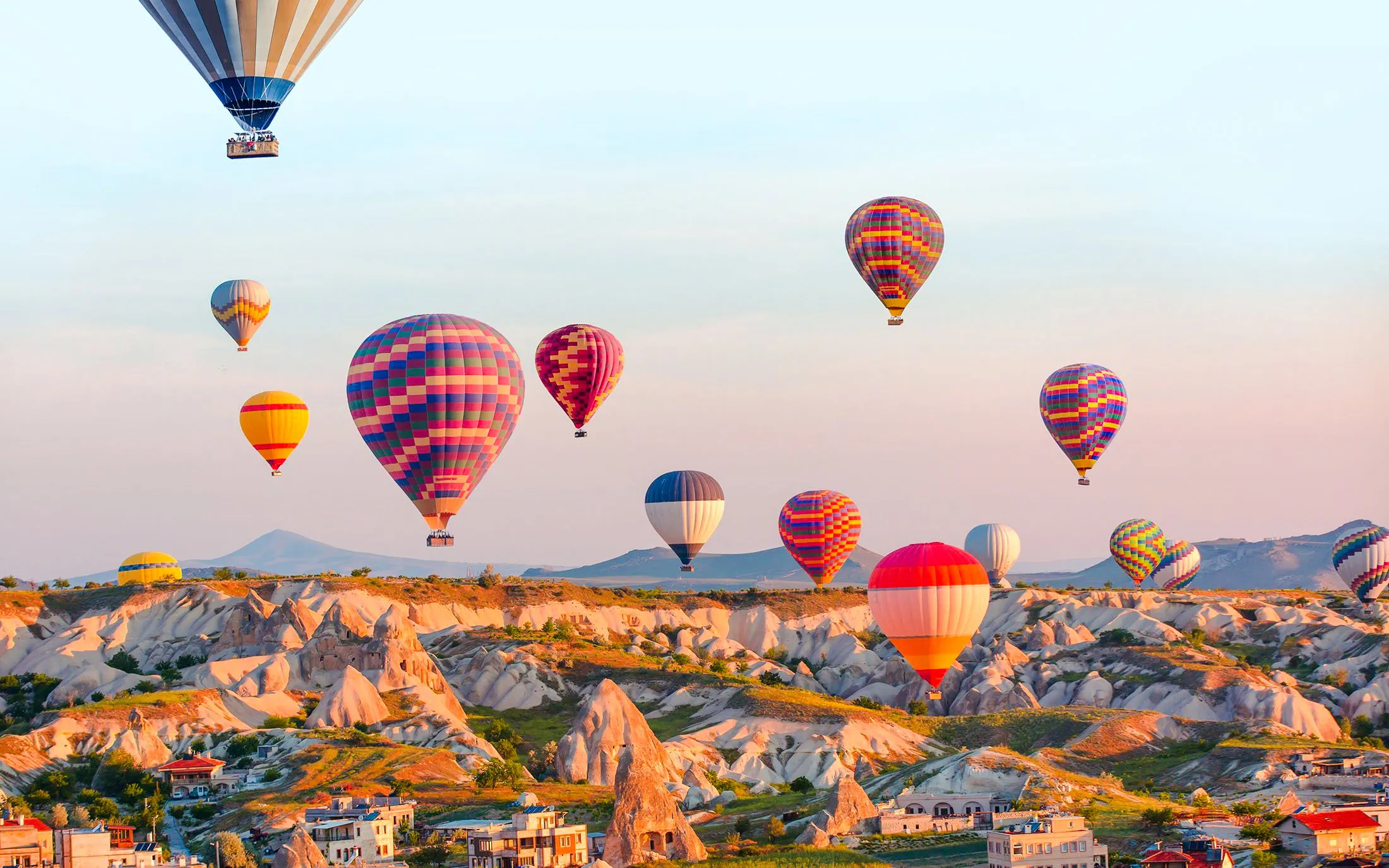 Hot air balloons over Cappadocia's unique rock formations during sunrise.