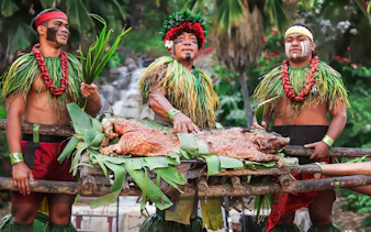 Traditional pig roast at Chief's Luau, Oahu, Hawaii with performers in cultural attire.
