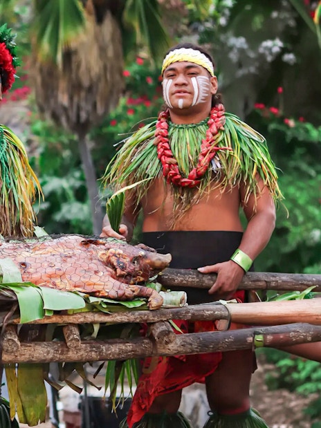 Traditional pig roast at Chief's Luau, Oahu, Hawaii with performers in cultural attire.