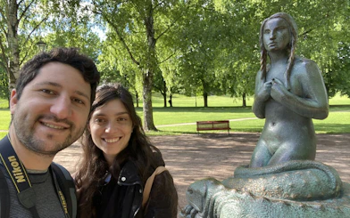 Visitors at Vigeland Park with a statue in Oslo.