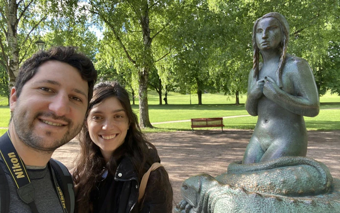 Visitors at Vigeland Park with a statue in Oslo.