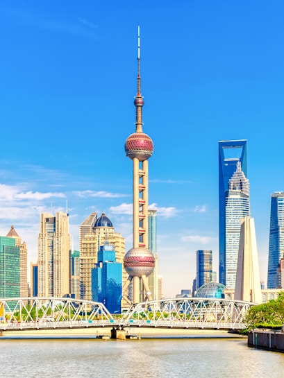 Oriental Pearl Tower in Shanghai skyline with modern skyscrapers and river.