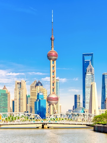 Oriental Pearl Tower in Shanghai skyline with modern skyscrapers and river.