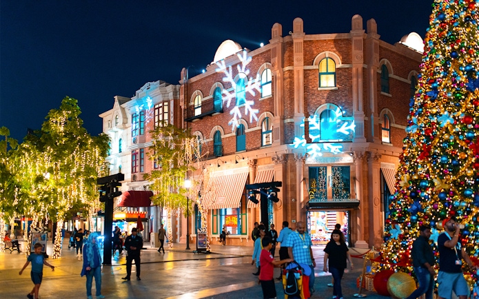 Festive decorations and visitors at MOTIONGATE™ Dubai during nighttime.