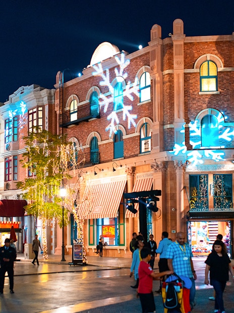 Festive decorations and visitors at MOTIONGATE™ Dubai during nighttime.