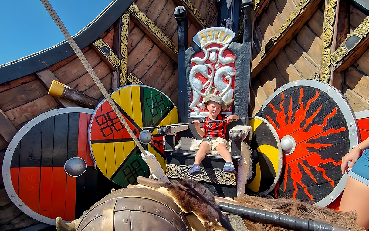 Child in Viking costume on themed cruise ship with shields and throne.