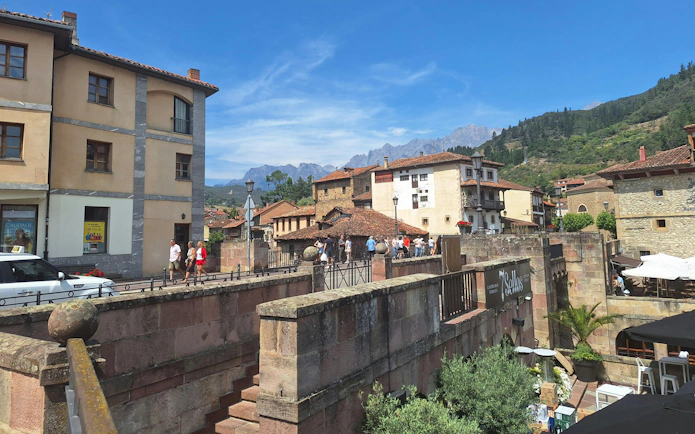 Street view of Potes, Cantabria with historic buildings and distant mountains.