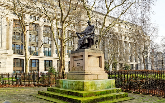 Charles James Fox bronze statue in Bloomsbury Square Garden, London with historic building backdrop.