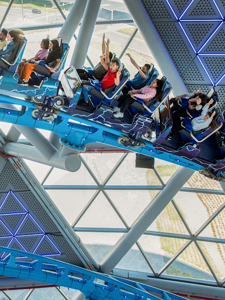Riders on The Storm Coaster in Dubai inside a futuristic glass structure.