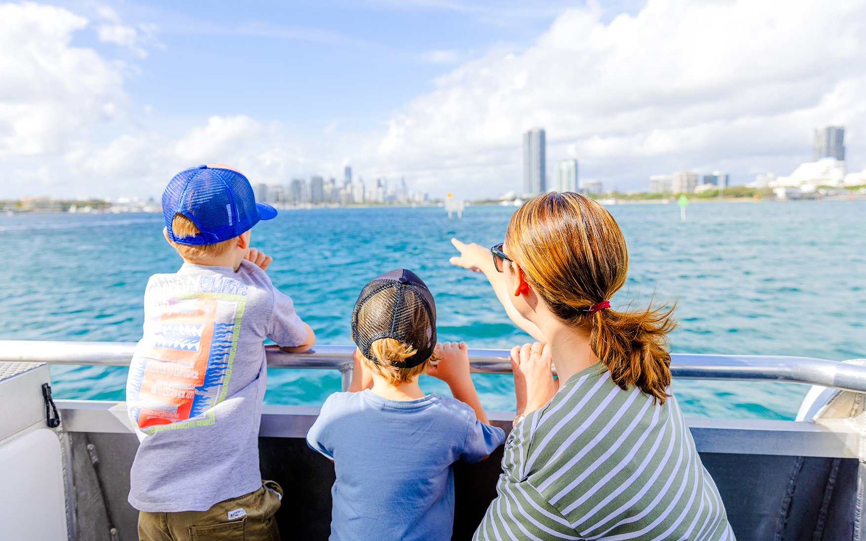 Kids and parents enjoying Gold Coast Hop-on Hop-off Boat Tour with city skyline in view.