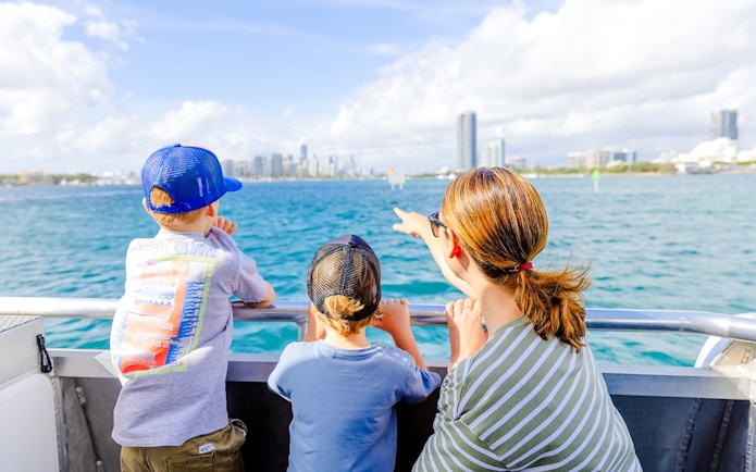 Kids and parents enjoying Gold Coast Hop-on Hop-off Boat Tour with city skyline in view.