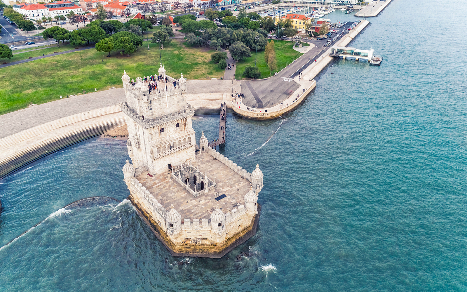 Aerial view of Belem Tower in Lisbon, Portugal, surrounded by water and nearby park.
