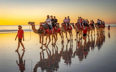 Camel ride along Tangier beach at sunset with tourists.