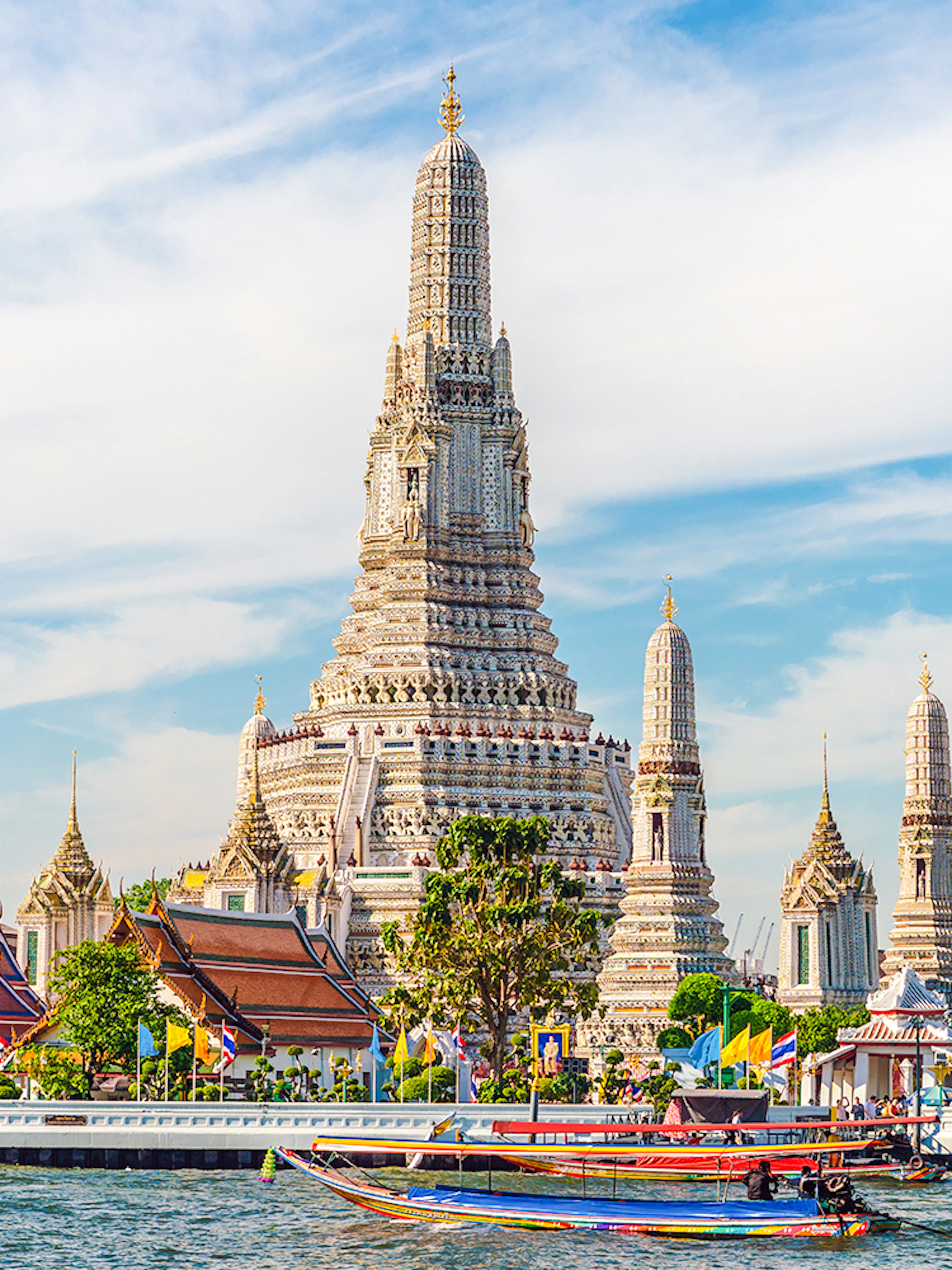 Wat Arun temple with colorful boats on Chao Phraya River, Bangkok, Thailand.